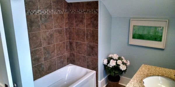 bathroom renovation with new tub brown tile shower surround, blue walls, and white trim