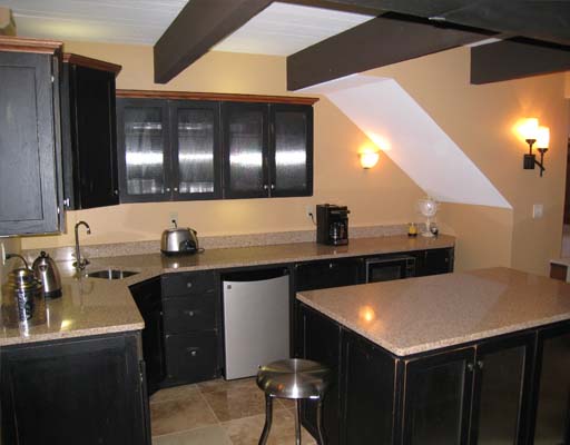 basement kitchenette with black cabinets and rustic beams